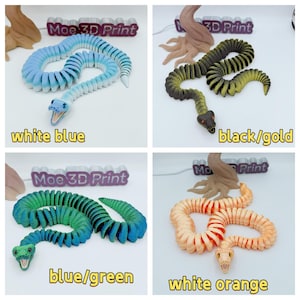 Op de afbeelding: Vier 3D-geprinte, beweegbare slangen in verschillende kleurencombinaties: wit en blauw, zwart en goud, blauw en groen en wit en oranje. Elke slang heeft een gedetailleerde kop en lichaam. De tekst "Moe 3D Print" is zichtbaar.