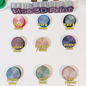 May include: Nine different color combinations of 3D printed round buttons with a spiral design. The colors include red and white, blue and white, black and white, purple and black, red and gold, purple and blue, purple, blue and green, gold and black, and red, yellow and blue.