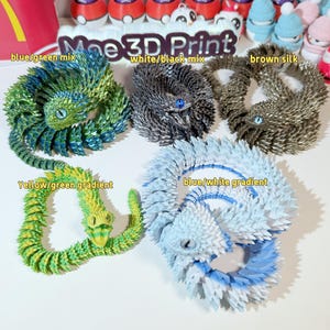 May include: Five 3D printed models of a lizard-like creature in different color combinations. The colors include blue and green, white and black, brown, yellow and green, and blue and white.