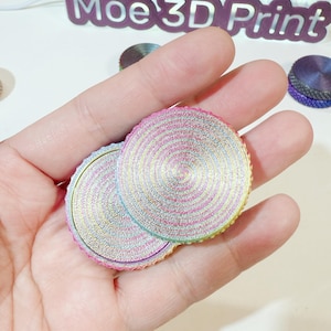 May include: Two round, iridescent, multi-colored, layered, decorative discs with a swirling pattern. The discs are made of a shiny, metallic material.