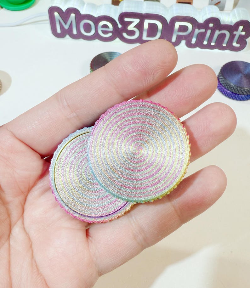 May include: Two round, iridescent, multi-colored, layered, decorative discs with a swirling pattern. The discs are made of a shiny, metallic material.