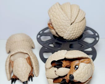 Könnte beinhalten: Drei Armadillo-Figuren, eine eingerollt zu einer Kugel, eine stehend und eine mit sichtbaren Beinen und Kopf in ihrem Panzer.