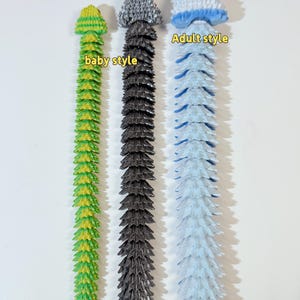 May include: Three 3D printed flexible toys in different colors and styles. The toy on the left is green and yellow and labeled "baby style". The middle toy is gray and the toy on the right is blue and white and labeled "Adult style".