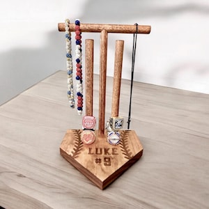 May include: Wooden baseball-shaped stand with three dowels for hanging necklaces and rings. The stand is engraved with the name "LUKE" and the number "#9".