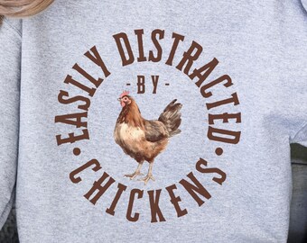 May include: A gray sweatshirt with the text "Easily Distracted - By - Chickens" in brown lettering and a brown chicken illustration.