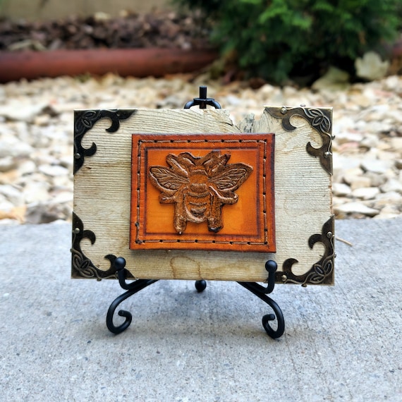 Tiny leather bee sculpted in intricate detail and framed in reclaimed wood with brass accents — this is the kind of thing you stop and stare at on someone's desk.