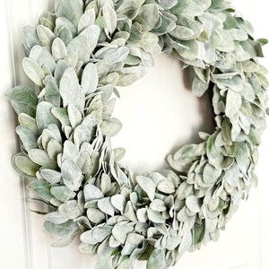 May include: A green and white faux lamb's ear wreath. The wreath is made of artificial leaves and is perfect for adding a touch of greenery to your home decor.