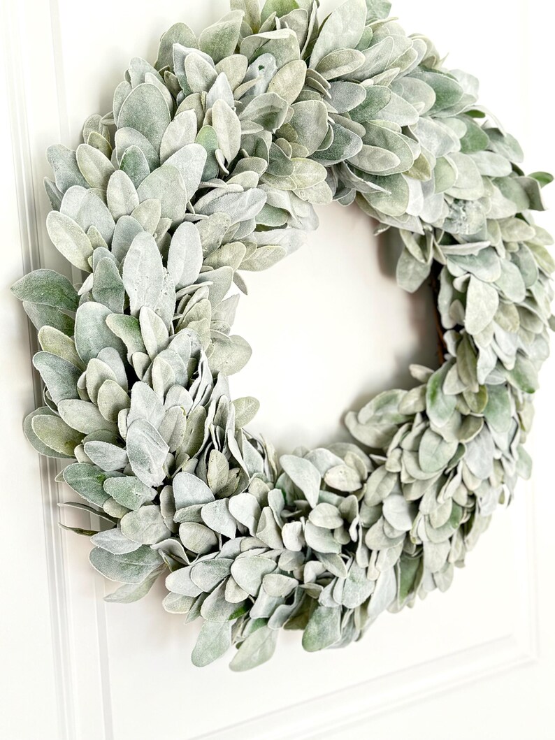 May include: A green and white faux lamb's ear wreath. The wreath is made of artificial leaves and is perfect for adding a touch of greenery to your home decor.