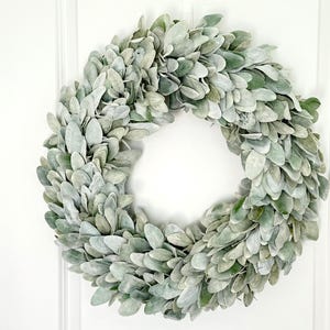 May include: A green and white faux lamb's ear wreath. The wreath is made of artificial leaves and is perfect for adding a touch of greenery to your home decor.