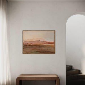 May include: An abstract landscape painting in a wooden frame hangs above a brown bench. The artwork features warm tones of brown, orange, and pink, depicting a mountainous terrain. The room has a neutral color palette with a white wall and a sheer curtain.