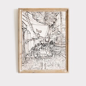 May include: Black and white line drawing of a Parisian street scene with a cafe on the cobblestone street. The cafe has tables and chairs with people sitting at them. There is a canopy over the cafe and buildings on either side of the street.