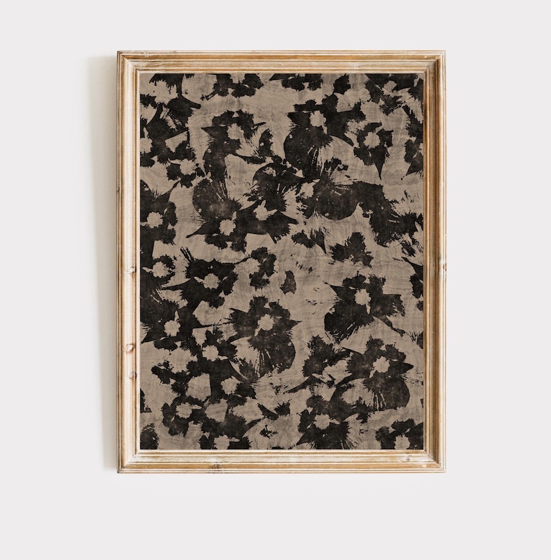 May include: A framed print with a black and white floral pattern on a beige background. The frame is a light wood color.