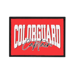 May include: A rectangular patch with a red background and a black border. The patch features the white text "COLORGUARD" in bold, block letters, with "Captain" written in cursive below.
