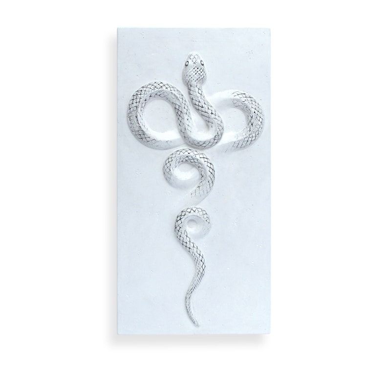 Op de afbeelding: Witte keramische wandkunst met een reli&euml;fdesign van een slang met een getextureerd, schubbig lichaam. De slang is verticaal opgerold, met de kop bovenaan en de staart onderaan.