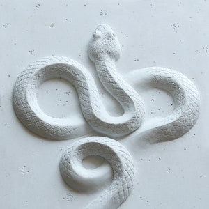 Op de afbeelding: Witte slangensculptuur met een getextureerd oppervlak, opgerold in een figuur acht.