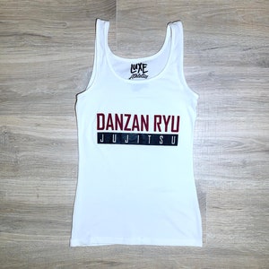 May include: White tank top with the text "LUXE Athletics" in black and red. The text "DANZAN RYU JUJITSU" is printed in black and red on the front of the tank top.