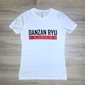 May include: White t-shirt with black text that reads "DANZAN RYU JUJITSU" in a red rectangle.