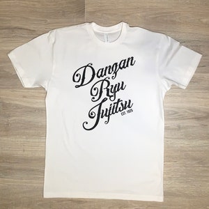 May include: White t-shirt with black text that reads "Dangan Ryu Jujitsu Est. 1925"