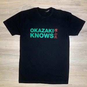 May include: Black t-shirt with the text "OKAZAKI KNOWS" in green and Japanese characters in red.