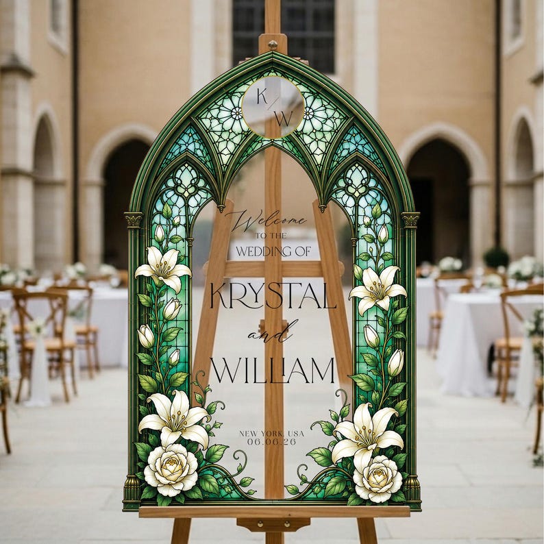 K&ouml;nnte beinhalten: Ein bogenf&ouml;rmiges Hochzeitsschild mit einem gr&uuml;nen Buntglasrahmen und Illustrationen von wei&szlig;en Lilien und Rosen. Der mittlere Text lautet: Welcome TO THE WEDDING OF KRYSTAL and WILLIAM NEW YORK, USA 06.08.26, mit den Initialen K/W im oberen Kreis.