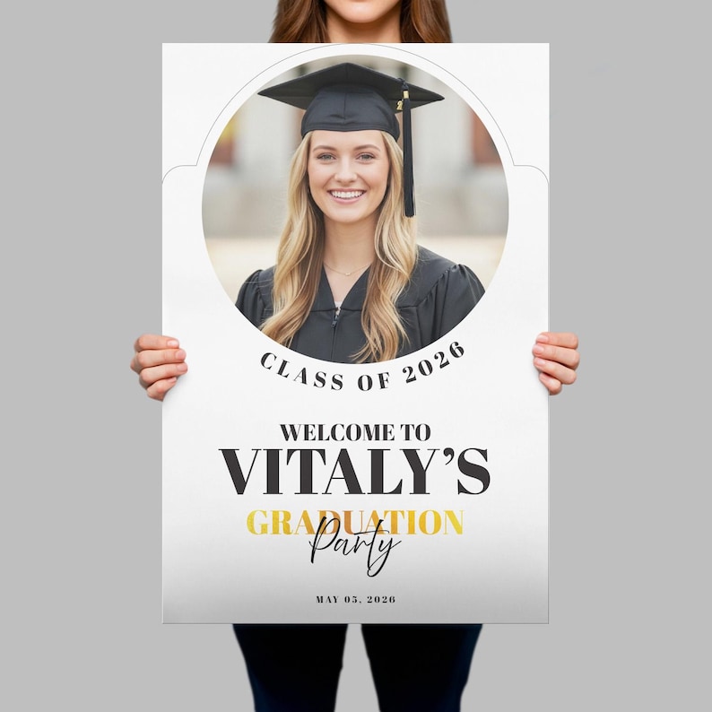 K&ouml;nnte beinhalten: Ein wei&szlig;es Schild f&uuml;r eine Abschlussfeier mit einem Foto einer l&auml;chelnden Absolventin in Hut und Robe. Auf dem Schild steht "Klasse von 2026" und "Willkommen zu Vitalys Abschlussfeier" in schwarzer und goldener Schrift. Das Datum "05. Mai 2026" ist ebenfalls angegeben.