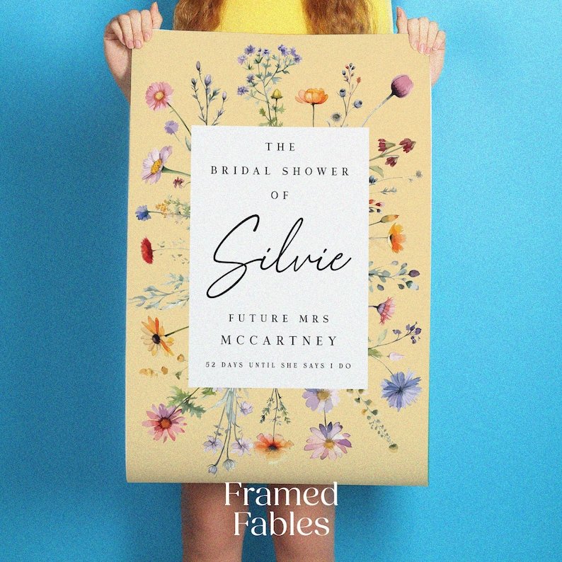 May include: A rectangular poster with a light yellow background featuring a white central panel. The text reads: THE BRIDAL SHOWER OF Silvie FUTURE MRS MCCARTNEY 52 DAYS UNTIL SHE SAYS I DO. The border is decorated with colorful watercolor wildflowers.