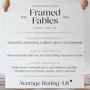 K&ouml;nnte beinhalten: Ein wei&szlig;es Schild, das von H&auml;nden gehalten wird, mit dem Text "Framed Fables" und den Jahren 2015 und 2024. Kundenbewertungen und eine durchschnittliche Bewertung von 4,8 Sternen werden darunter angezeigt. Das Schild enth&auml;lt auch den Text "CUSTOM SIGNS WITH PHOTO".