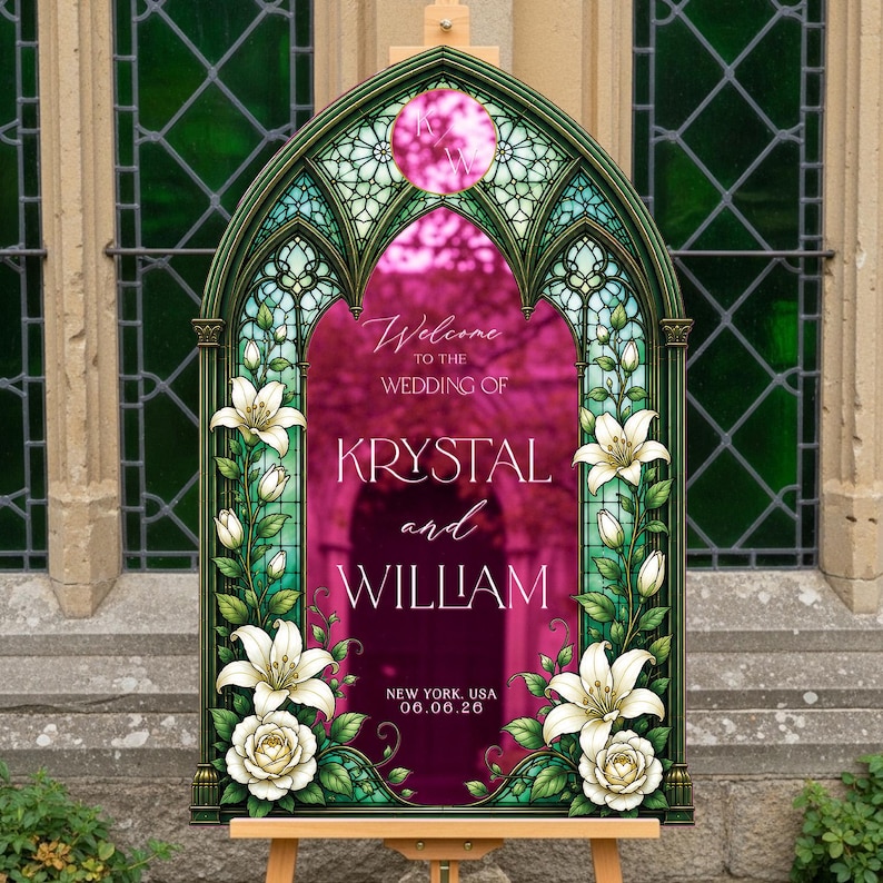 K&ouml;nnte beinhalten: Ein bogenf&ouml;rmiges Hochzeitsschild mit einem Buntglasrahmen-Design, verziert mit wei&szlig;en Lilien und Rosen. In der Mitte steht der Text: Welcome to the wedding of Krystal and William, New York, USA, 06.06.26, mit einem kreisf&ouml;rmigen Monogramm oben.