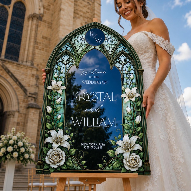K&ouml;nnte beinhalten: Ein bogenf&ouml;rmiges Hochzeitsschild mit dunkelgr&uuml;nem Rahmen, Buntglas-Optik, wei&szlig;en Lilien und Rosen. Der Text in der Mitte lautet: Welcome to the wedding of Krystal and William, New York, USA, 06.06.26, erg&auml;nzt durch ein K/W-Monogramm.