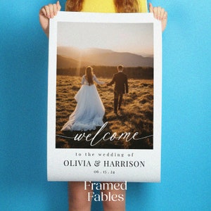 May include: A wedding welcome sign with a photo of a couple walking away from the camera in a field. The sign says "Welcome to the wedding of Olivia & Harrison 06.15.24" and "Framed Fables".