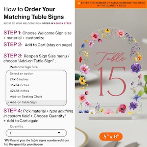 May include: An arched clear acrylic table sign featuring a colorful floral border with pink, purple, yellow, and blue wildflowers. The sign displays the text "Table 15" in a pink serif font. An orange label at the bottom indicates 8 x 6 inches.