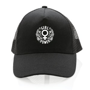 Op de afbeelding: Zwarte truckercap met een witte afbeelding van een vrouwelijk symbool in een krans met de woorden "Girl Power" eromheen.