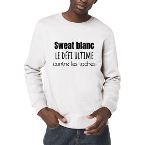 Op de afbeelding: Wit sweatshirt met zwarte tekst die "Sweat blanc le défi ultime contre les taches" luidt.