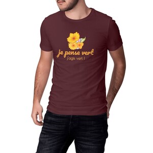 Pode incluir: Uma camiseta marrom com um gráfico de flores amarelas e o texto "je pense vert j'agis vert!"