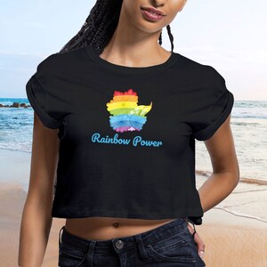 Op de afbeelding: Een zwart gecropped T-shirt met een regenboogbloemendesign en de tekst "Rainbow Power" in blauw.