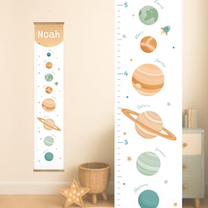May include: A children's height chart featuring a space theme. The chart displays planets like Earth, Mars, Jupiter, Saturn, Uranus, and Neptune. The chart is white with a wooden top and bottom, and the name "Noah" is printed at the top.