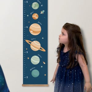 May include: A vertical wall growth chart featuring a dark blue background with illustrations of planets including Earth, Mars, Jupiter, Saturn, Uranus, and Neptune, along with stars and a rocket, labelled with numerical markings from 2 to 5 feet.
