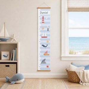 May include: A nautical-themed height chart with the name "Daniel" at the top. The chart features illustrations of a lighthouse, sailboat, whale, and other sea-related images. The background is light blue with horizontal stripes, and the chart is designed to measure up to 6 feet.