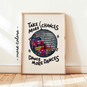 May include: A motivational poster with a disco ball and the text "Take More Chances Dance More Dances". The disco ball is colorful and has a black outline. The text is in black and white.
