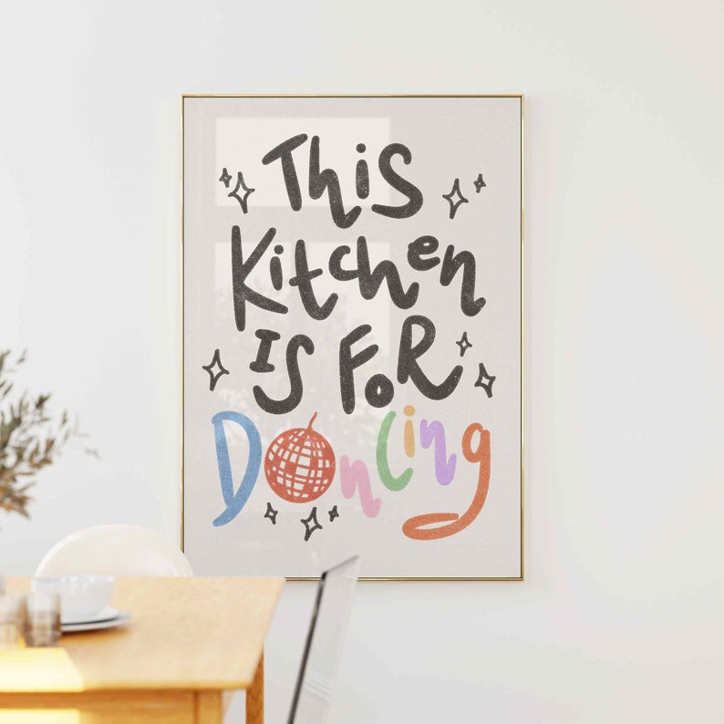 May include: A framed art print with the words "This Kitchen Is For Dancing" in a playful font. The text is in black, with the word "Dancing" in multiple colors. A disco ball graphic is included.