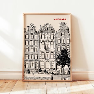 May include: A framed black and white print of Amsterdam canal houses. The word "AMSTERDAM" is printed in red at the top. The artwork features detailed illustrations of buildings, a tree, and people on bicycles.