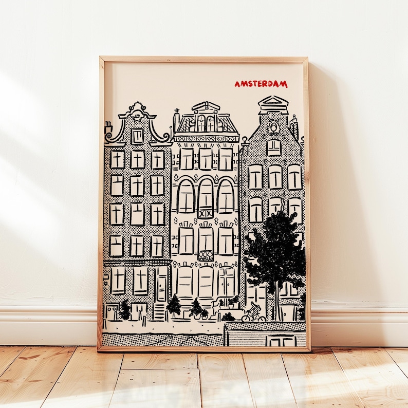 May include: A framed black and white print of Amsterdam canal houses. The word "AMSTERDAM" is printed in red at the top. The artwork features detailed illustrations of buildings, a tree, and people on bicycles.