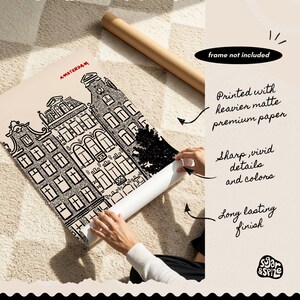 May include: Black and white architectural print of Amsterdam buildings, with the city name in red. The print is on matte paper and rolled up. Text on the image says "frame not included", "Printed with heavier matte premium paper", "Sharp, vivid details and colors", and "Long lasting finish".