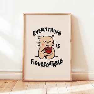 Peut inclure: Une affiche encadrée représentant un chat de dessin animé buvant dans une tasse rouge. Le texte "EVERYTHING IS FIGUREOUTABLE" est au-dessus et en dessous de l'illustration du chat. L'œuvre est sur fond crème, encadrée de bois clair.