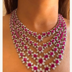 Puede incluir: Un collar de varias capas con un diseño floral que presenta piedras preciosas rosas y diamantes transparentes.
