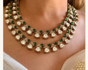 May include: A double-strand necklace with a gold chain and white and green gemstones. The necklace features a design of teardrop-shaped stones with smaller stones surrounding them.