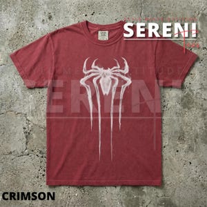 Puede incluir: Camiseta roja carmes&iacute; con un emblema de ara&ntilde;a blanco. La camiseta de manga corta y cuello redondo tiene la palabra "SERENI" impresa en blanco. La palabra "CRIMSON" est&aacute; impresa en la parte inferior.