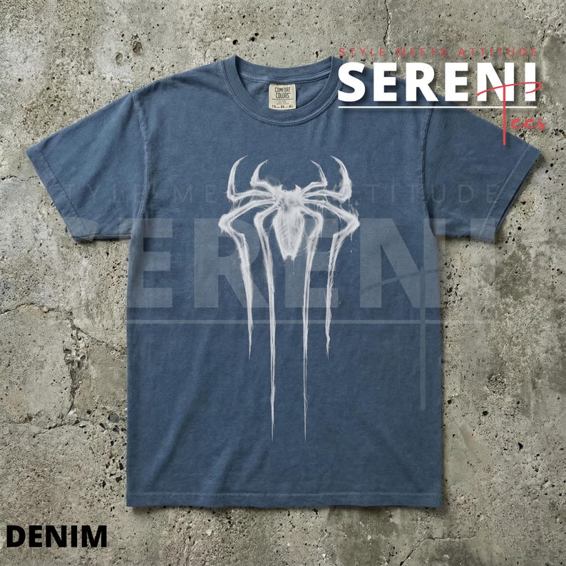Puede incluir: Camiseta azul denim con un gr&aacute;fico de ara&ntilde;a blanco. El gr&aacute;fico tiene un dise&ntilde;o estilizado con l&iacute;neas largas y goteantes. La camiseta tiene cuello redondo y mangas cortas. La palabra "SERENI" est&aacute; impresa en blanco en la esquina superior derecha.