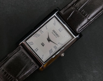 Vintage, gerenoveerd Seiko Slim Quartz herenhorloge met witte wijzerplaat, bruine band en 26 mm kast.