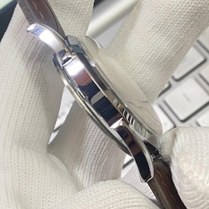 May include: A silver wristwatch with a brown leather band. The watch has a round face and a silver case.